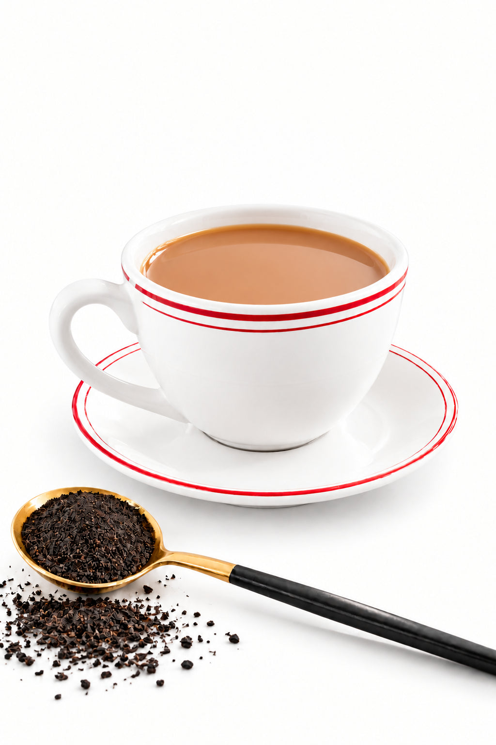 A white ceramic cup of milk tea, resting on a matching saucer next to a gold spoon filled with loose black tea, set on a white marble table.